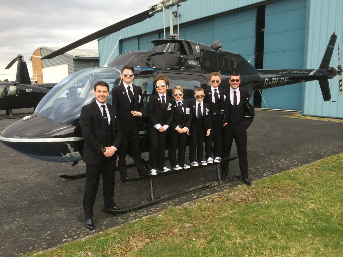 Mr Ginn and his stylish page boys in their dinner suits propped up again a helicopter which they flew in on