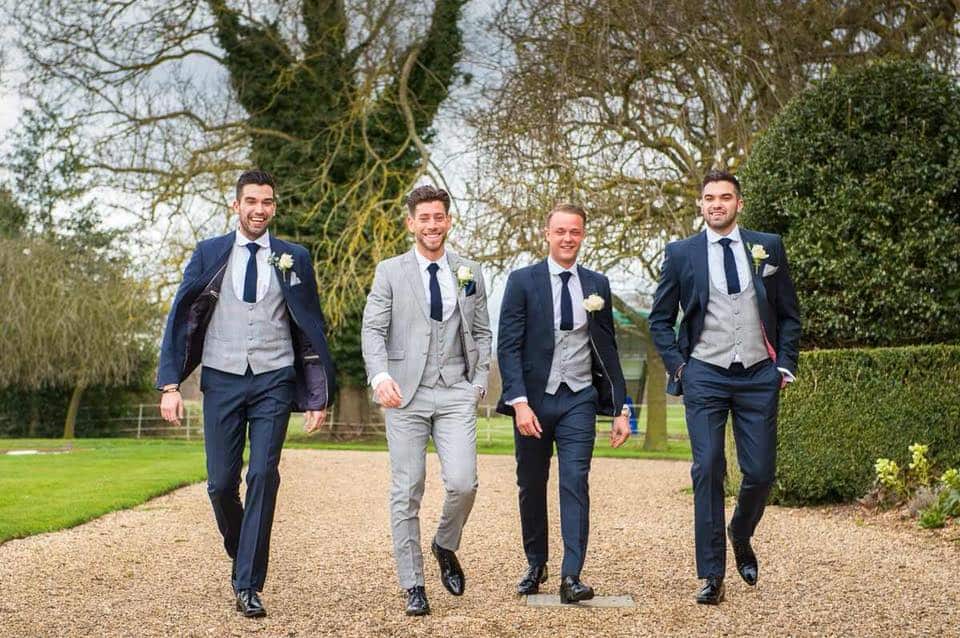 Groom in a full grey Prince of Wales suit. Groomsmen in navy hire suits with Prince of Wales waistcoats to match the Groom.