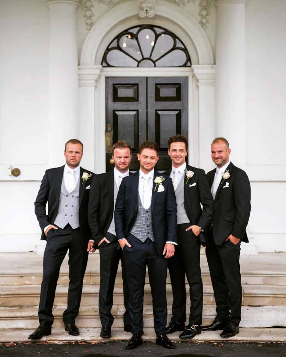 Mr Jardine in black lounge suits. Groom dogtooth waistcoat rest in assorted Ascot grey styles